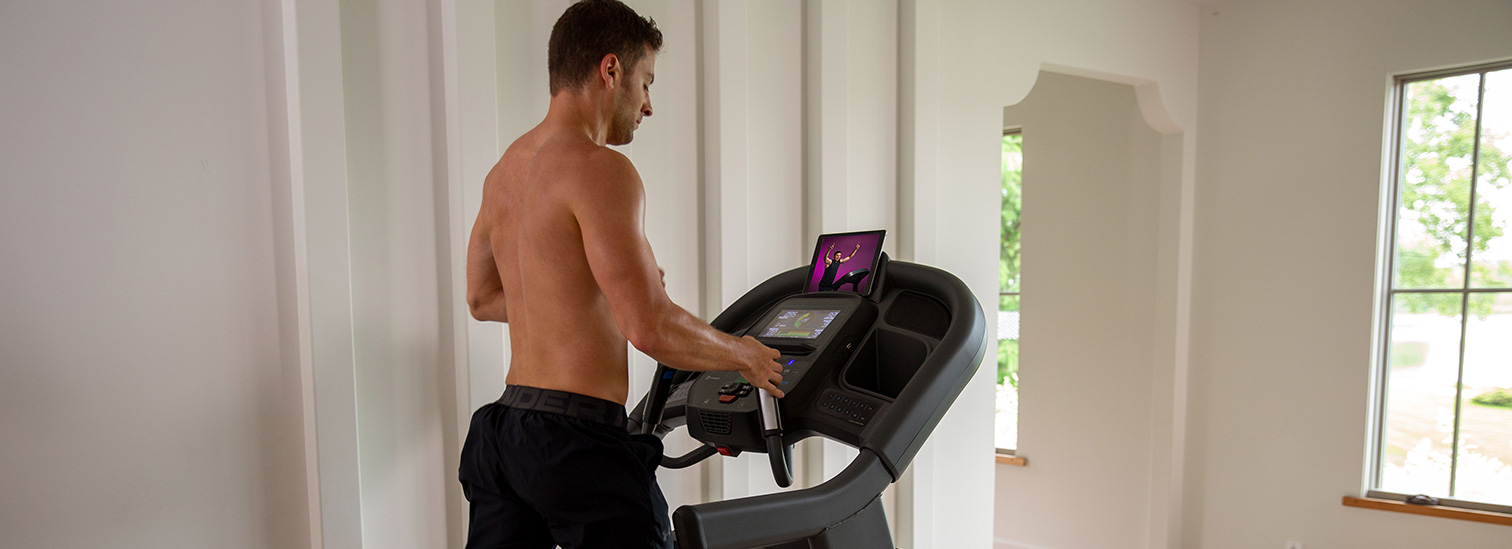 Man running on Horizon 7.8 AT treadmill interacting with fitness app