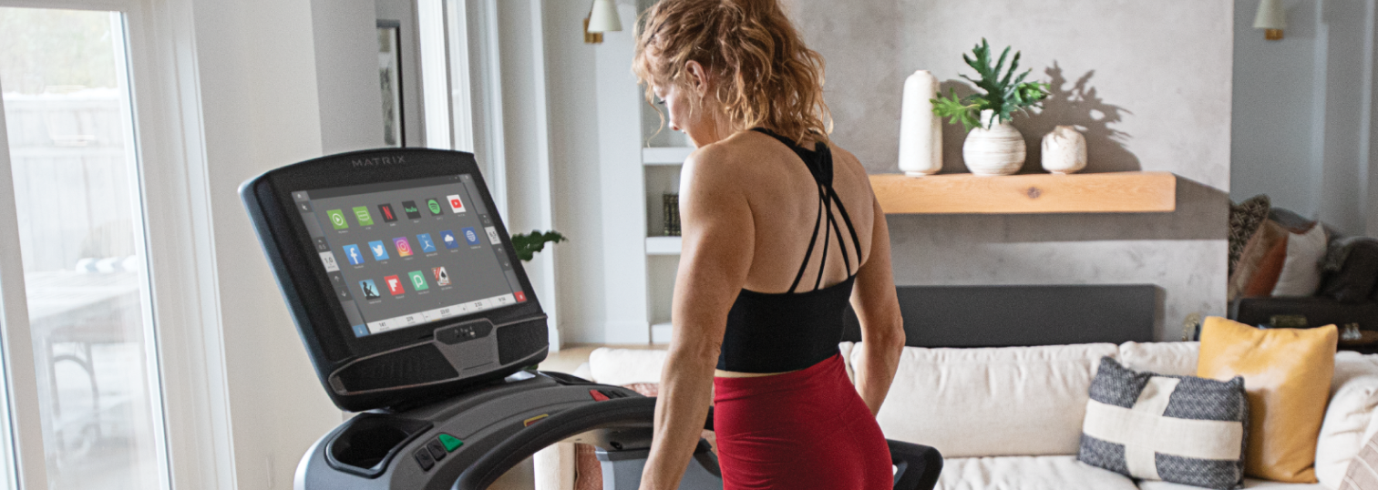 Woman standing on Matrix treadmill interacting with console