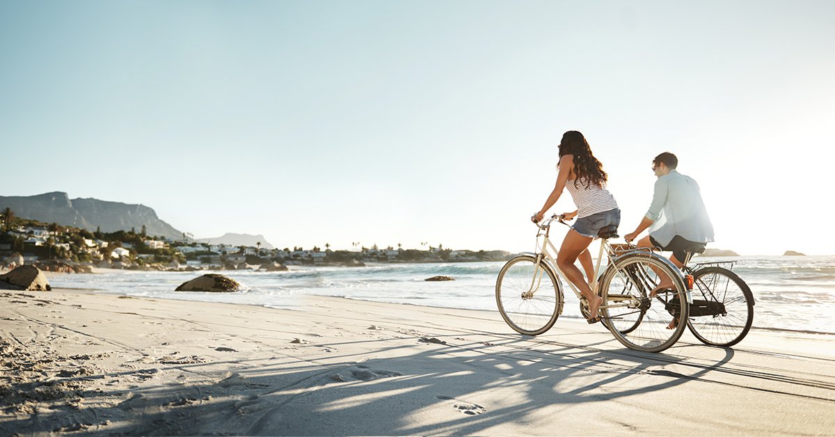 A boy and a girl biking on a sandy beach.