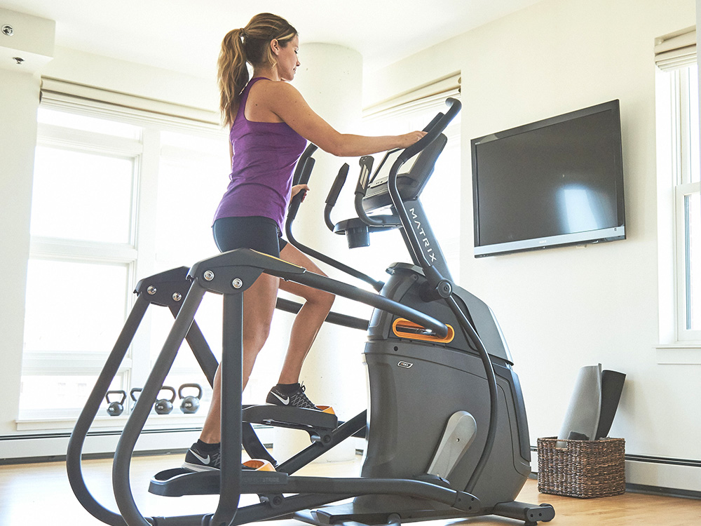 A woman is exercising and doing a HIIT elliptical workout.